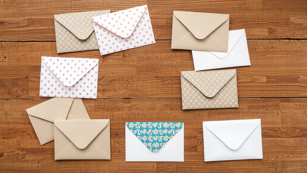 Various handmade envelopes with different patterns and colors arranged on wooden surface, no text no words no letters