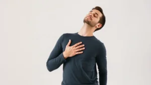 Man practicing diaphragmatic breathing with proper posture, hand on belly, relaxed shoulders, clear studio lighting, focused expression