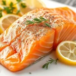 Close-up of fresh salmon fillet on white cutting board with lemon slices and fresh herbs, professional food photography, bright natural lighting, detailed texture visible