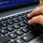 Close-up of a Windows keyboard showing the numeric keypad with numbers highlighted, hands positioned for typing Alt codes, professional home office setting