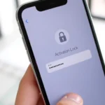 Close-up of iPhone screen showing Activation Lock login prompt with Apple ID field and password entry, hands holding device, modern home interior background, natural lighting