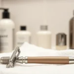 Close-up of quality razor and shaving cream bottles on clean white towel, bathroom setting, professional grooming products